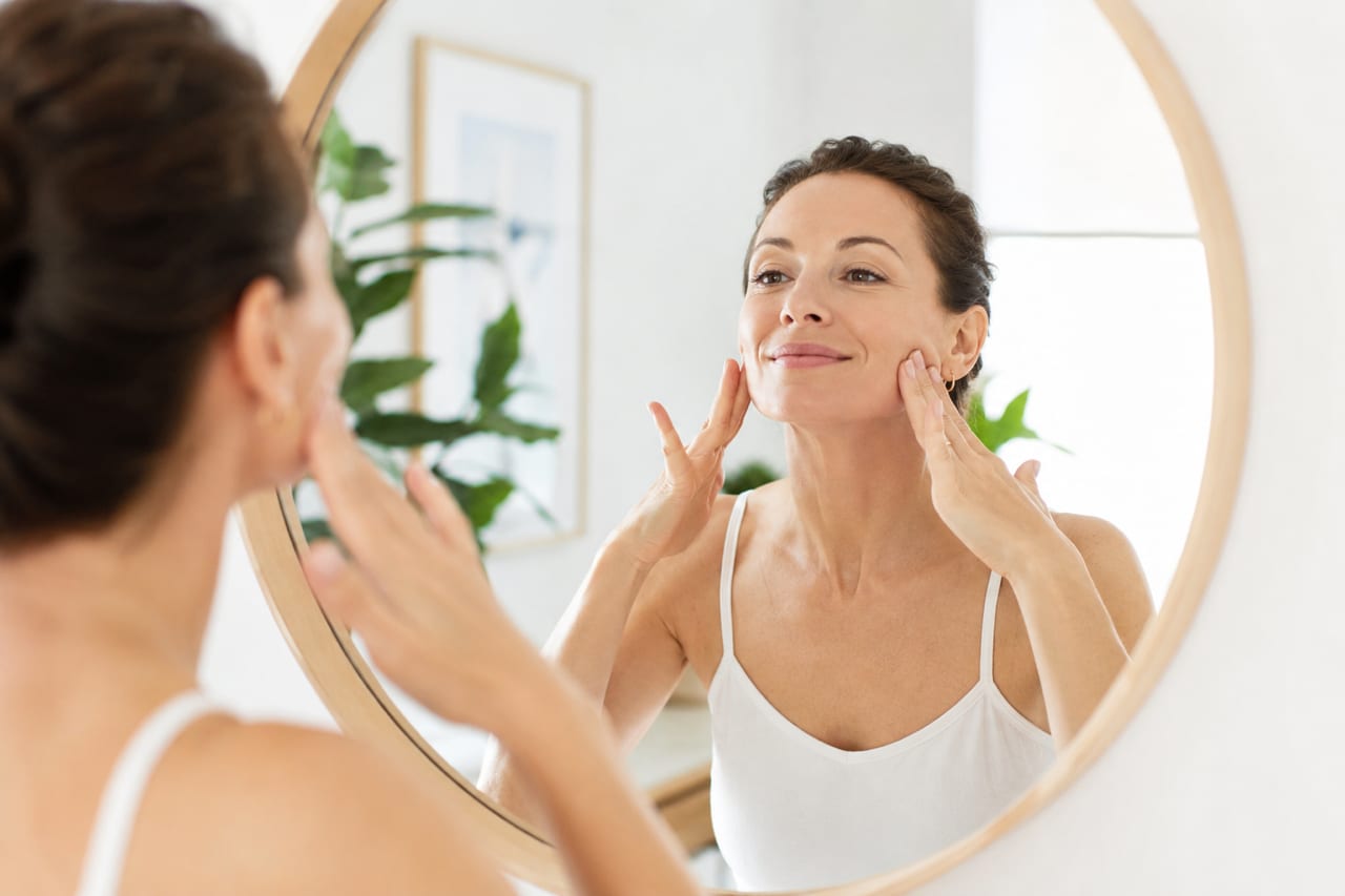 Femme pratiquant le yoga du visage devant un miroir rond